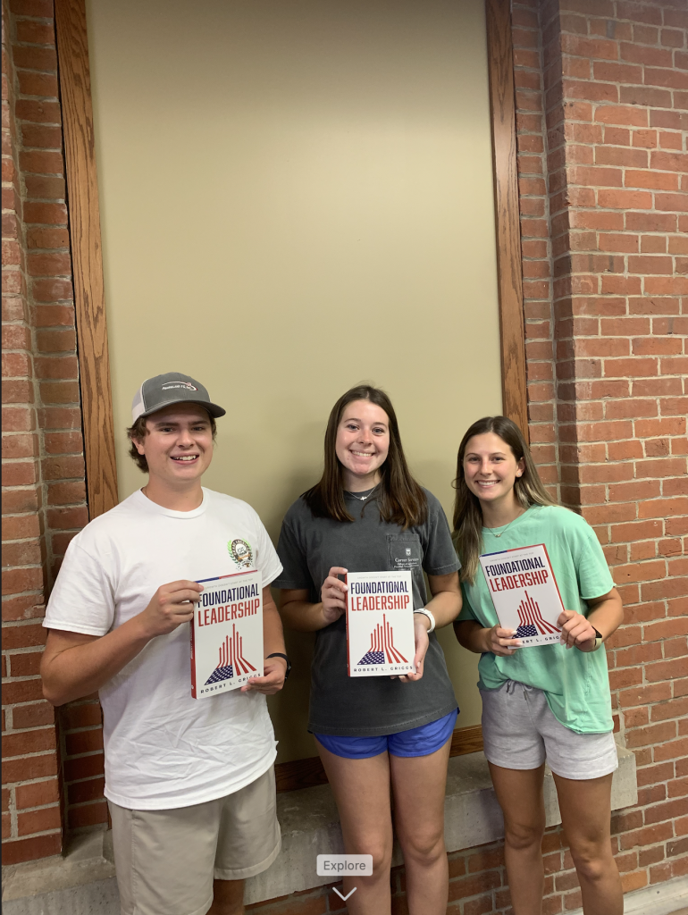 Students with a copy of Foundational Leadership by Robert Griggs